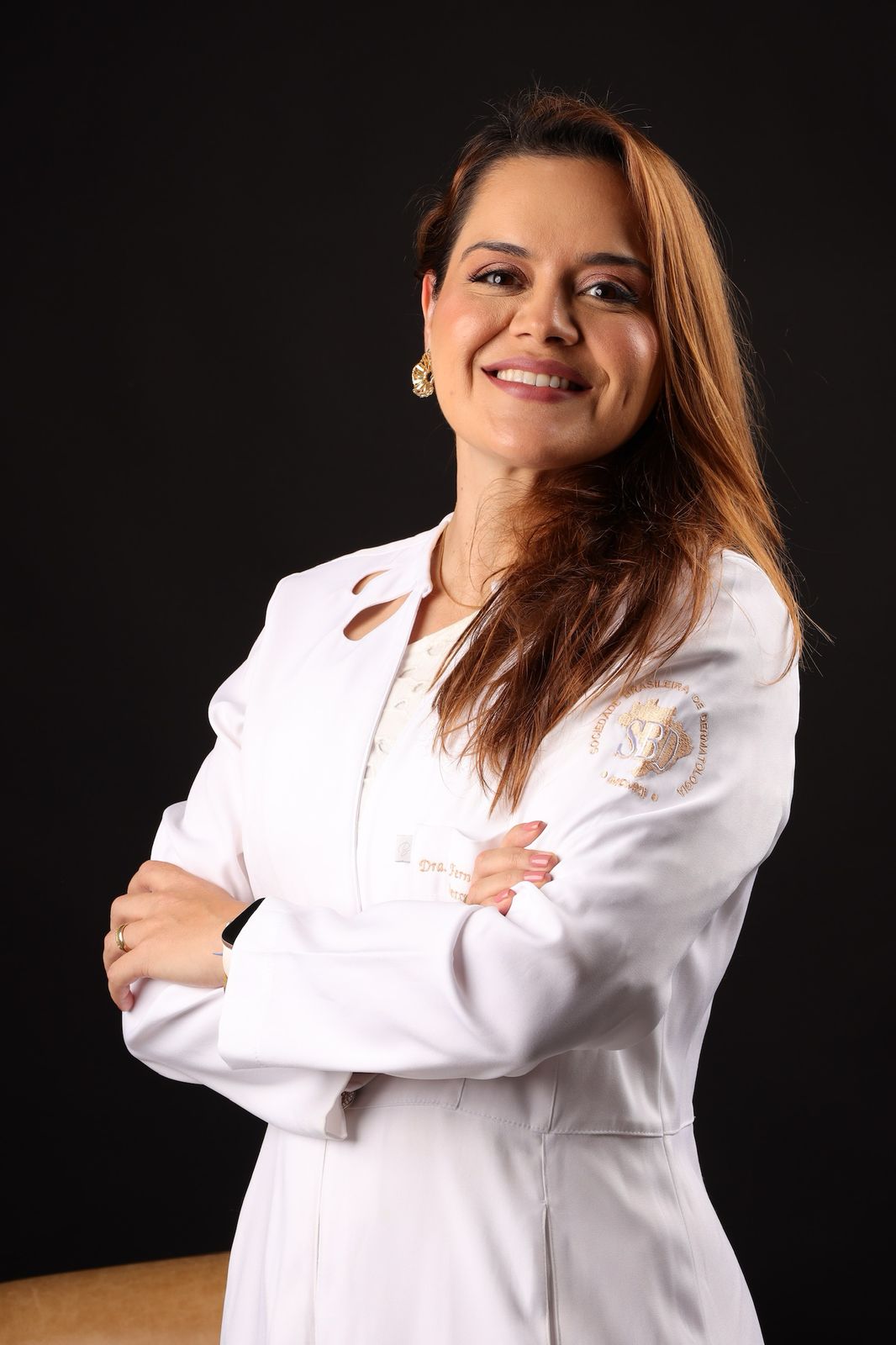 Dra. Fernanda Ventin de jaleco branco, com os braços cruzados
