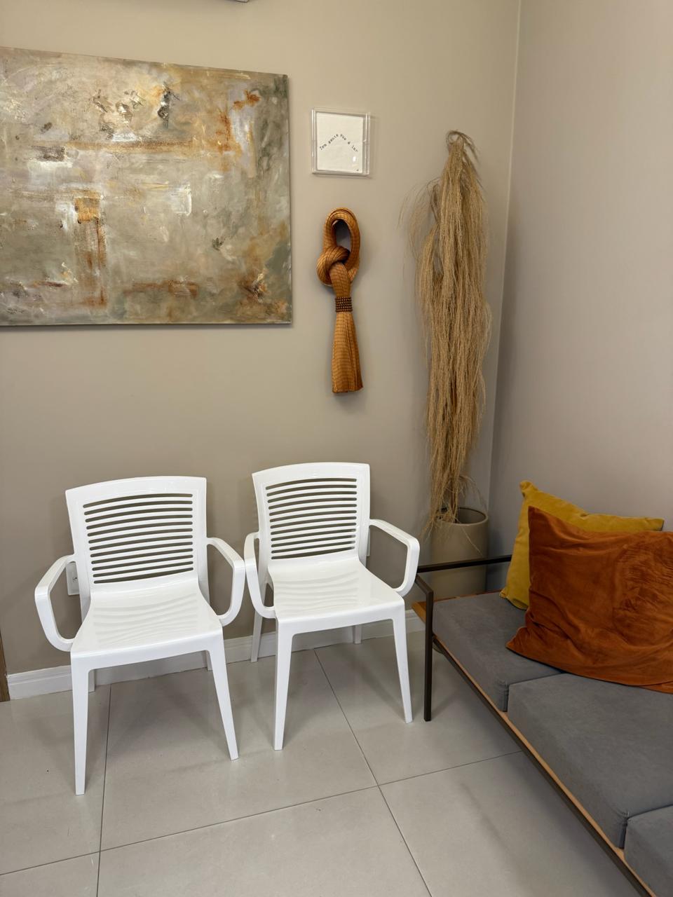 Sala de espera do consultório na Pituba, com cadeiras brancas e quadro
